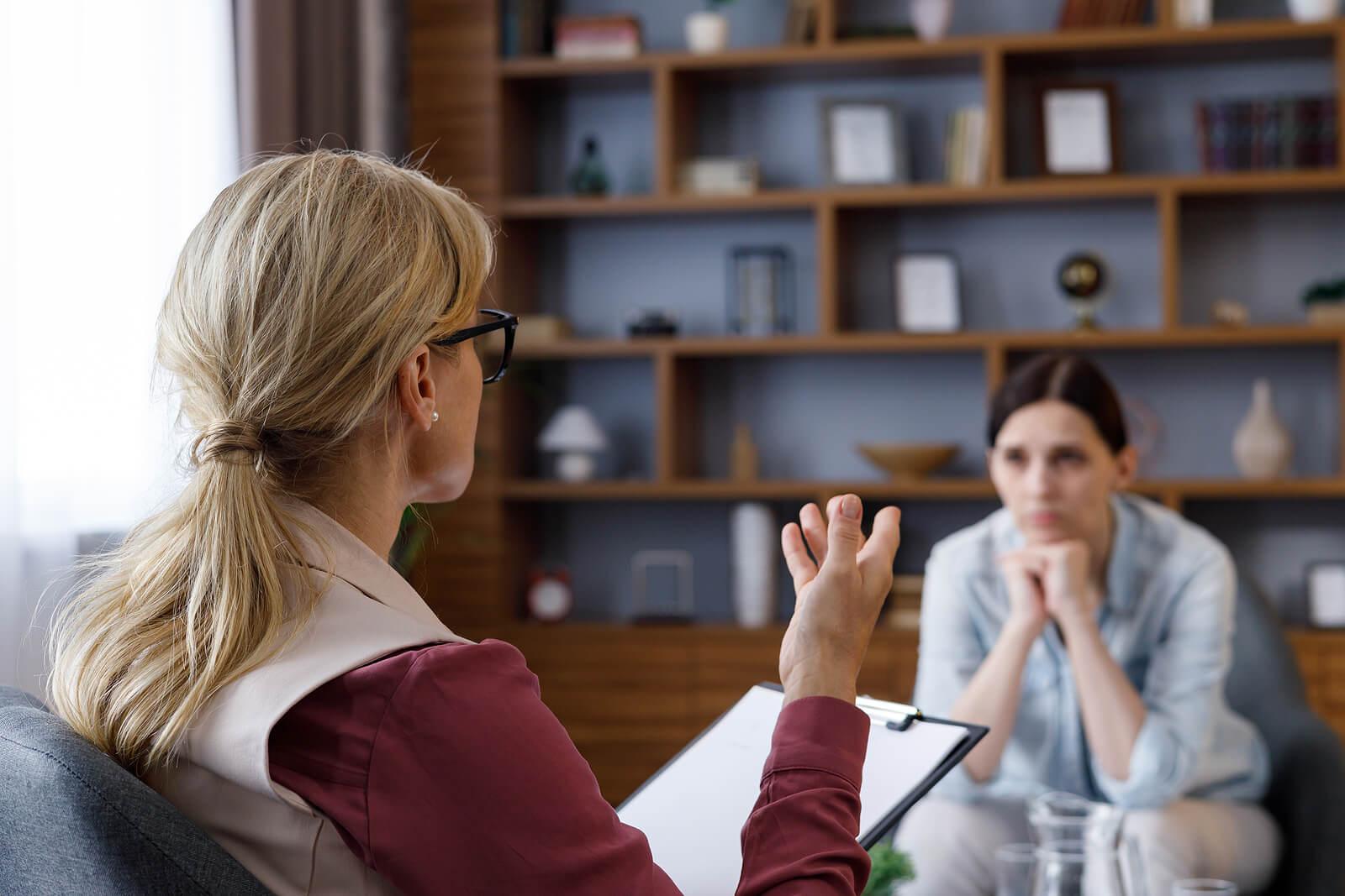 Image of a woman sitting in a chair listening to a female therapist. If you struggle with your emotions and behaviors, find support with Adult IOP in Houston, TX.