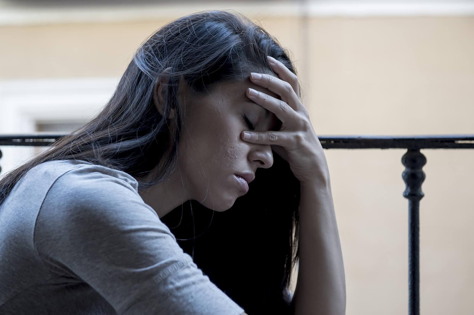 Image of a sad woman closing her eyes and covering her face with her hands. Begin to cope and heal with your hopelessness with the support of Adult IOP in Houston, TX.