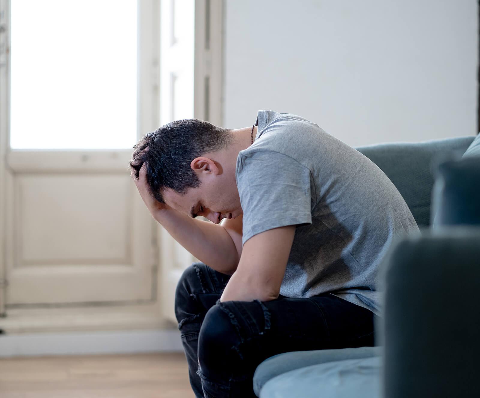 Image of a depressed man sitting on a couch running a hand through his hair. Begin coping with your chronic depression and start healing with the help of adult IOP in Houston, TX.