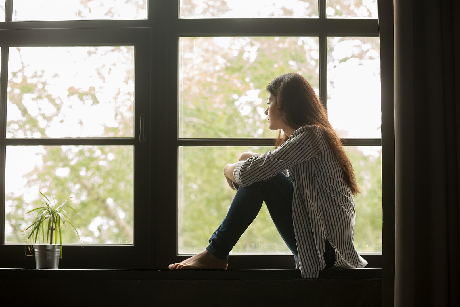 Image of a thoughtful woman sitting in a window sill. With an adult intensive outpatient program in Houston, TX you can begin healing from your chronic depression.