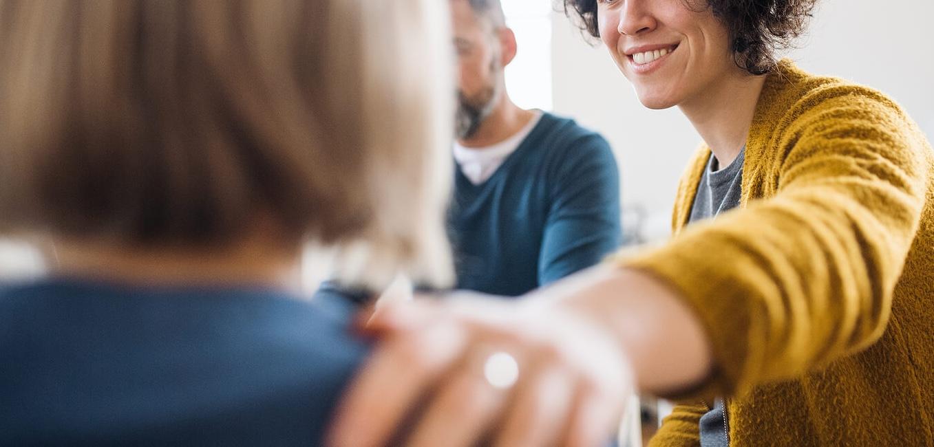 Image of a woman touching another woman shoulder in comfort. Begin to build real life skills to manage your emotions and strengthen your relationships with the help of adult intensive outpatient program in Houston, TX.