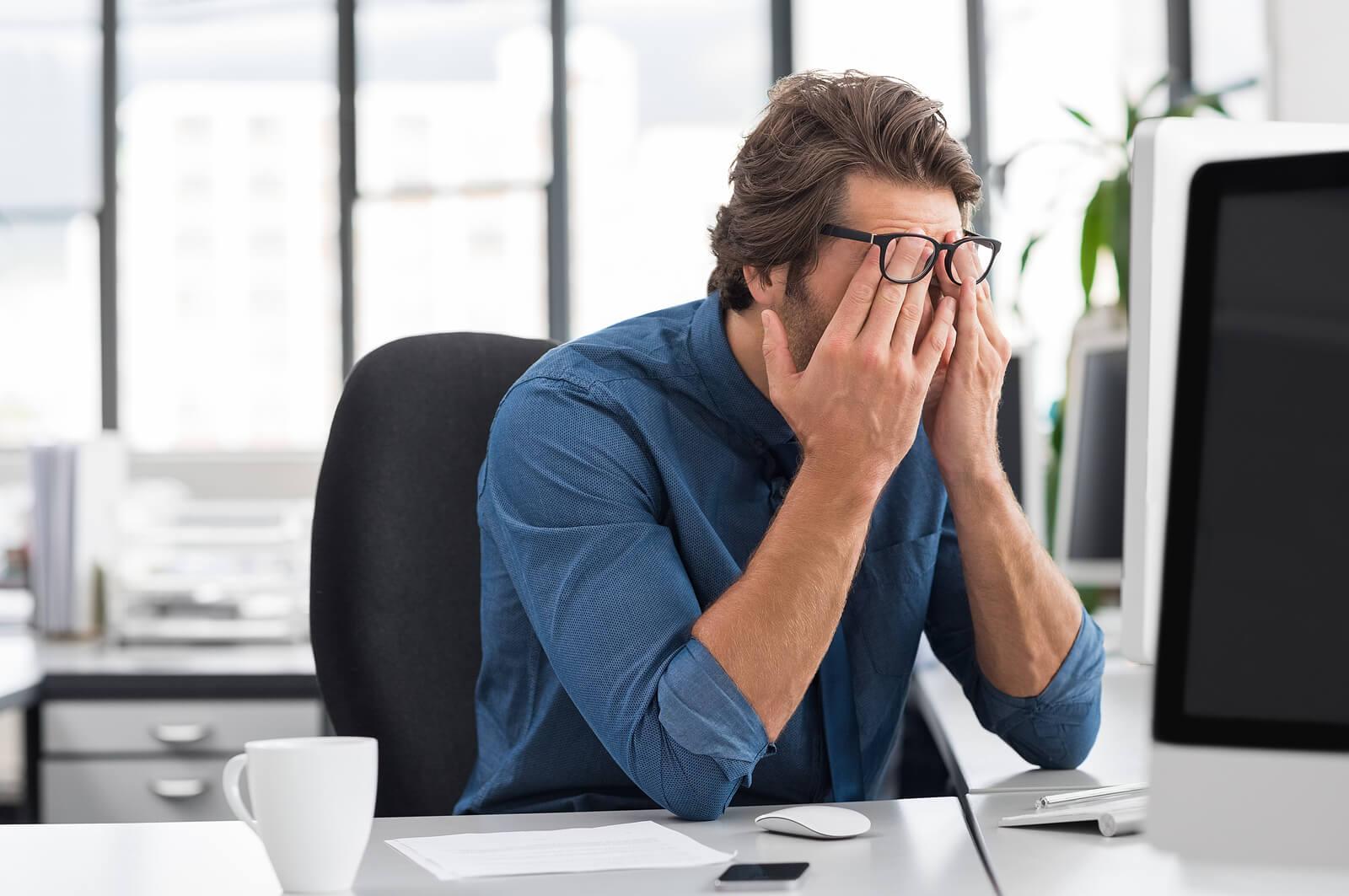 Image of a stressed man sitting in an office covering his face. With the support of an adult IOP in Houston, TX you can begin coping with your anxiety symptoms in positive ways.