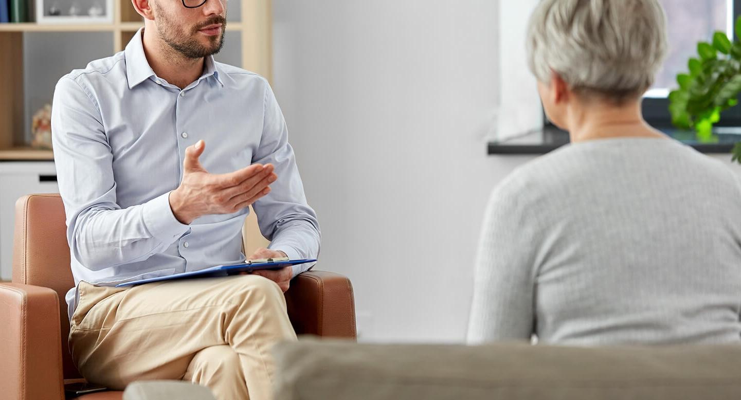 Image of a therapist holding a clipboard talking to a woman sitting on a couch. Find support with managing your emotions with the help of adult intensive outpatient program in Houston, TX.