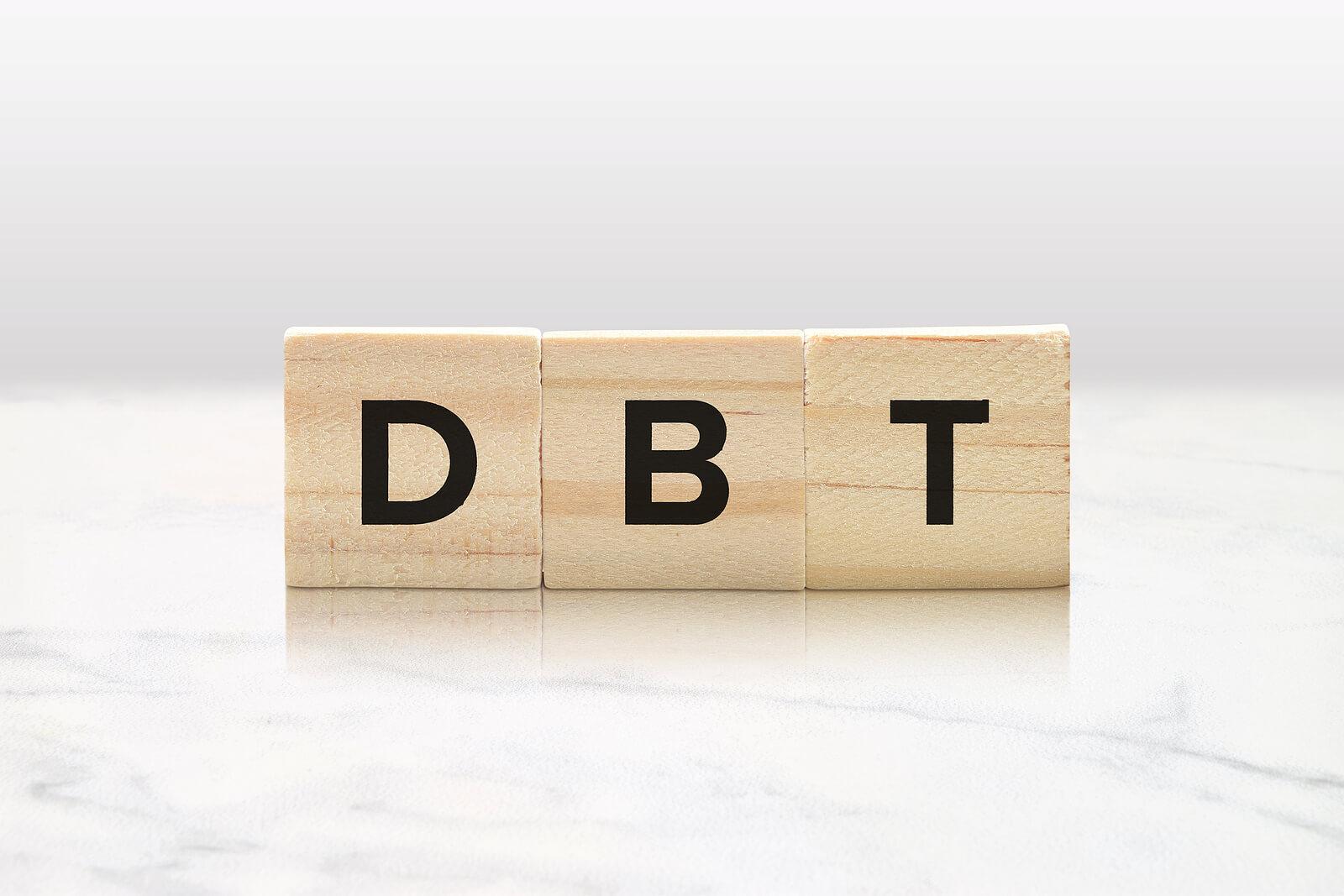 Image of three wooden blocks that spell DBT. An adult IOP in Houston, TX can help you map out the patterns of your life that lead to emotional distress and the skills to cope.