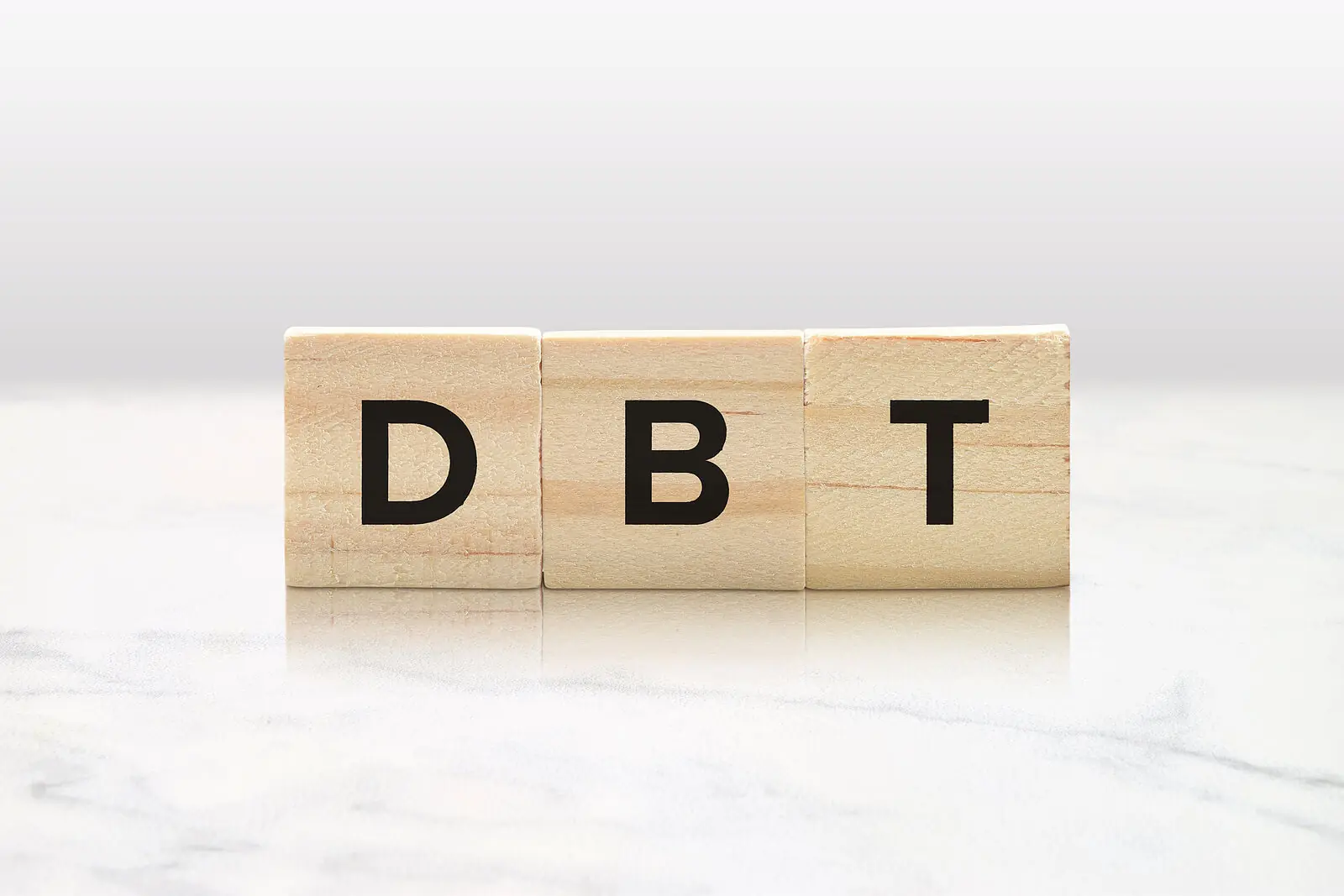 Image of three wooden blocks that spell DBT. An adult IOP in Houston, TX can help you map out the patterns of your life that lead to emotional distress and the skills to cope.