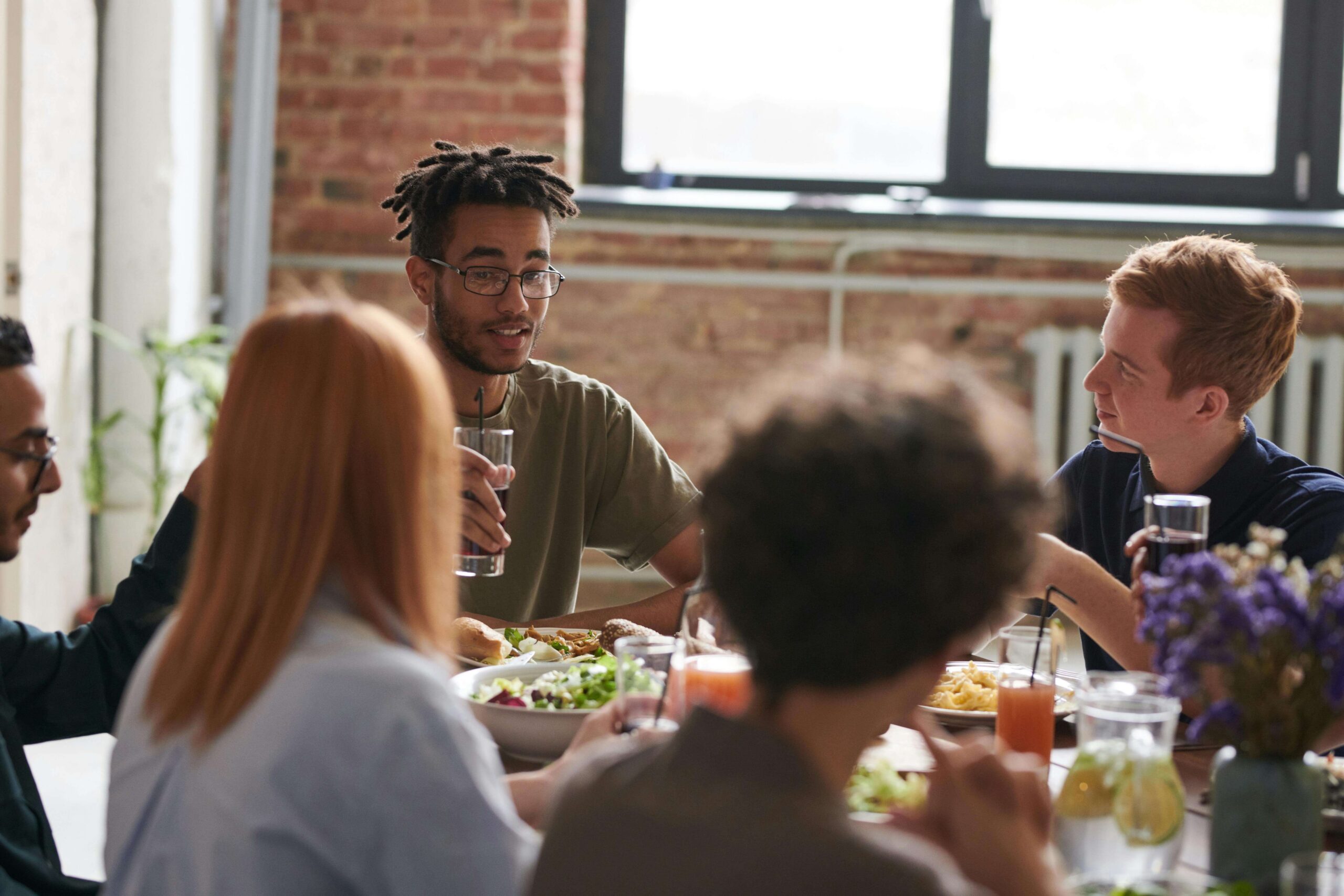 Image of a happy diverse group of people sitting at a table eating. With the help of an adult IOP in Houston, TX you can learn the DBT skills you need to manage your emotions in healthy ways.