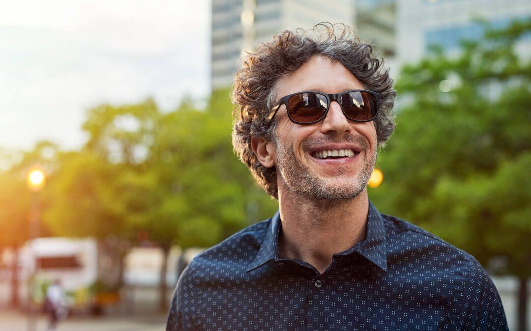 Image of a smiling mature man walking outside with sunglasses on. Begin improving your impulse control and take back your life with the help of DBT used in an Adult IOP in Houston, TX.