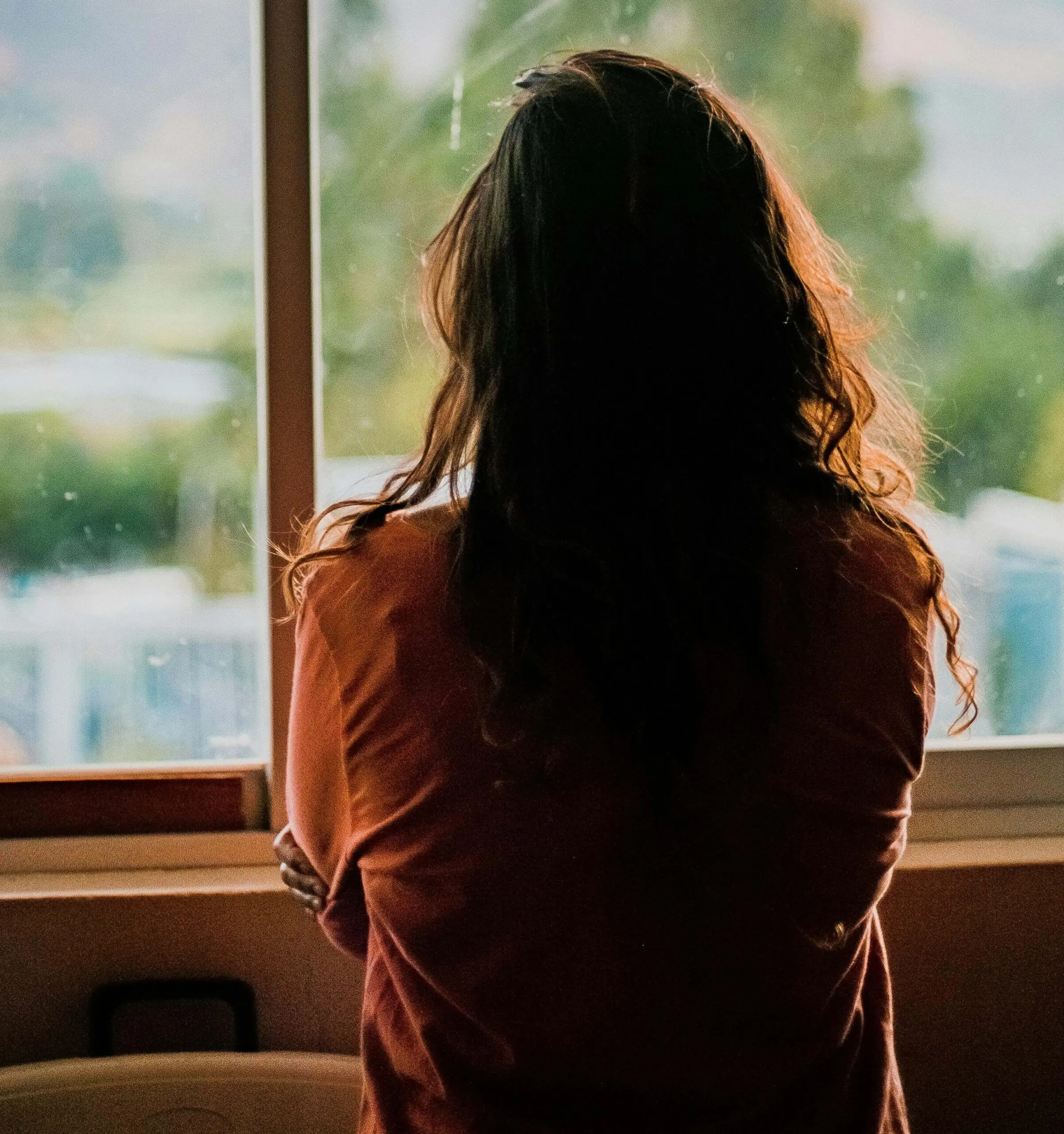 Sad woman looking out window. Learn to control your emotions and behaviors by overcoming your unhealthy patterns with the help of a DBT used in an adult intensive outpatient program in Houston, TX.