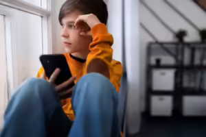 male teen tearful looking at phone