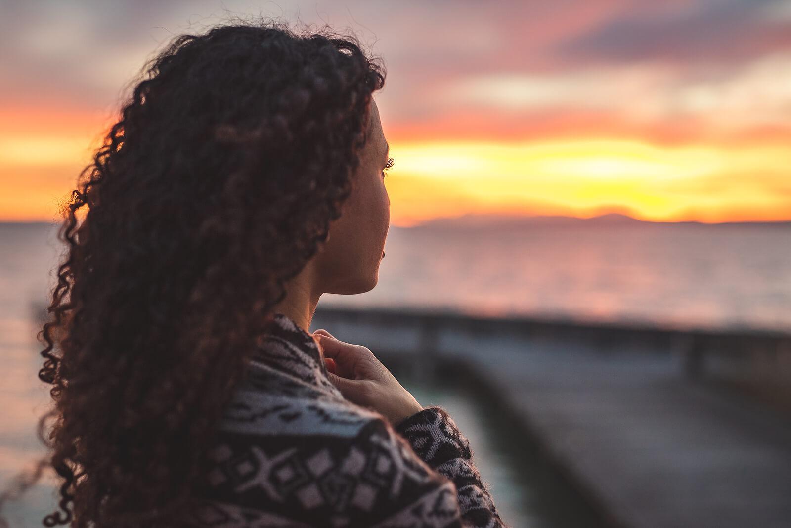Peaceful woman looking at the ocean as the sun sets. Overcome your perfectionistic thinking and begin healing with the help of perfectionism treatment in Houston, TX.