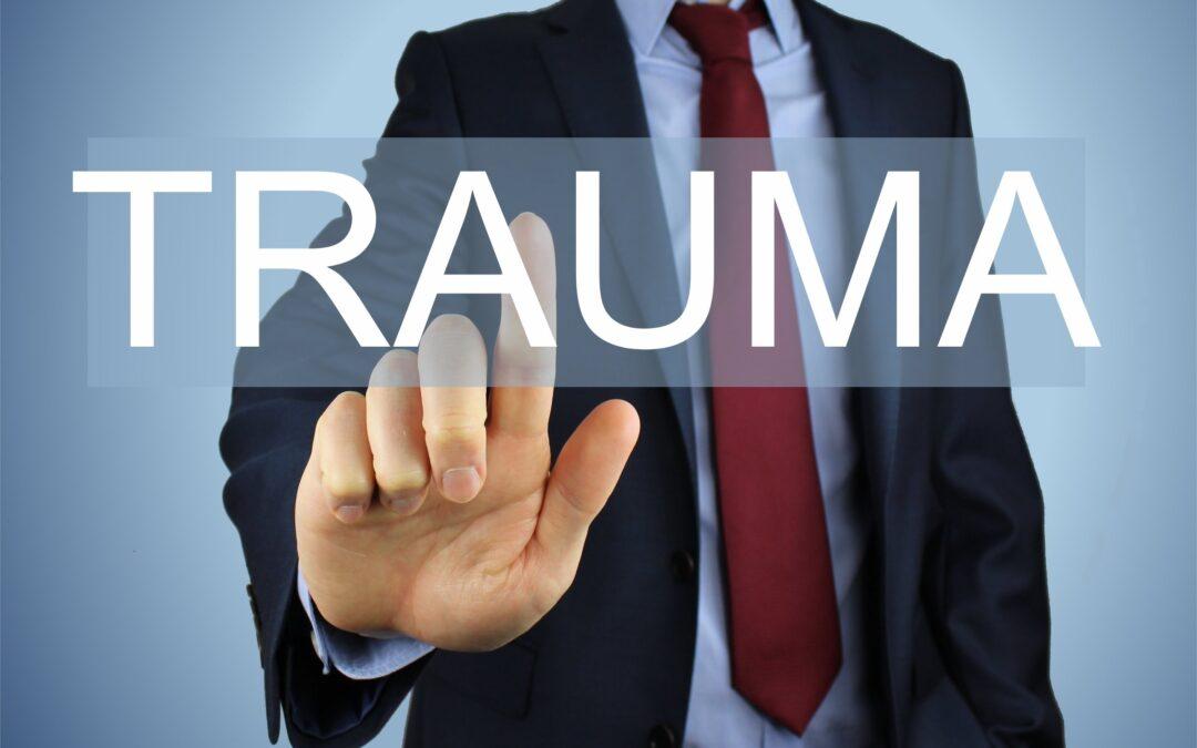 The word "trauma" written in large letters across the chest of a male with a finger to the word