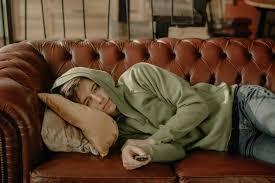 Teen boy laying on couch with remote