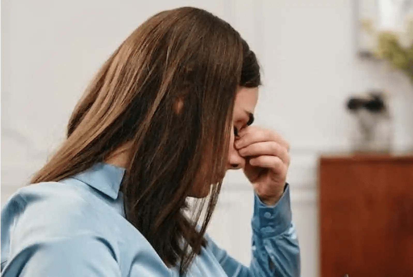 Woman looking down, holding face