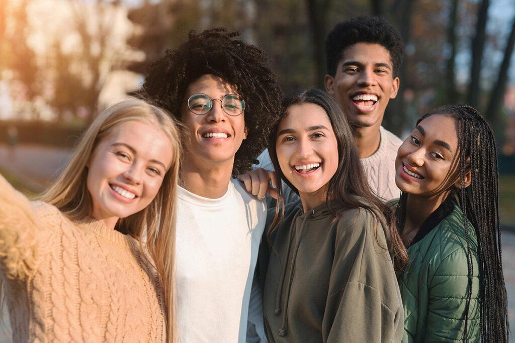 4 teens standing together in a group, smiling